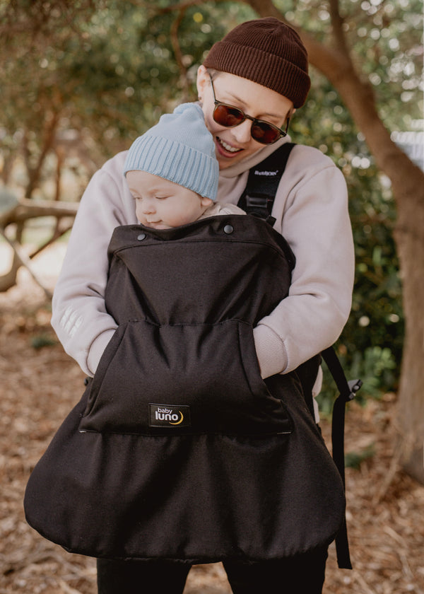 Parent holding a child in a black baby carrier with the baby luno Carrier Cocoon Winter Cover