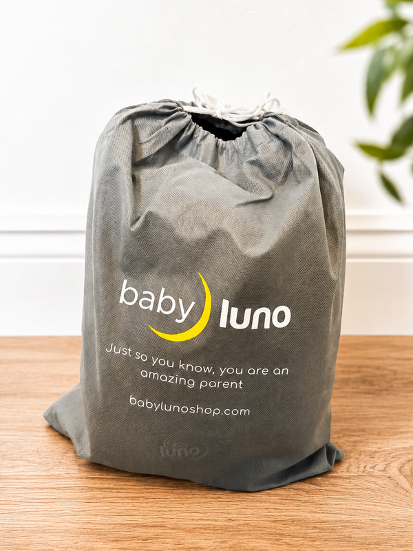 Gray drawstring bag with 'baby luno' branding on a wooden surface.