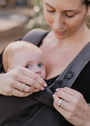 Woman attaching the baby luno Carrier Cocoon Winter Cover to her ErgoBaby baby carrier.