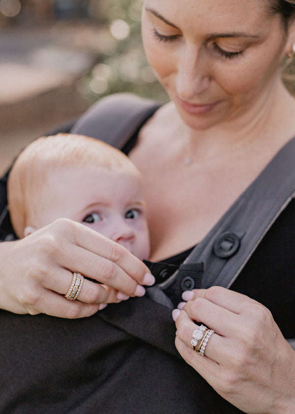 Woman attaching the baby luno Carrier Cocoon Winter Cover to her ErgoBaby baby carrier.